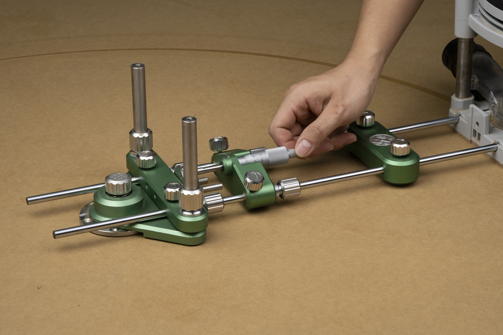 Green router circle-cutting system with guide rails mounted on workbench, hand adjusting