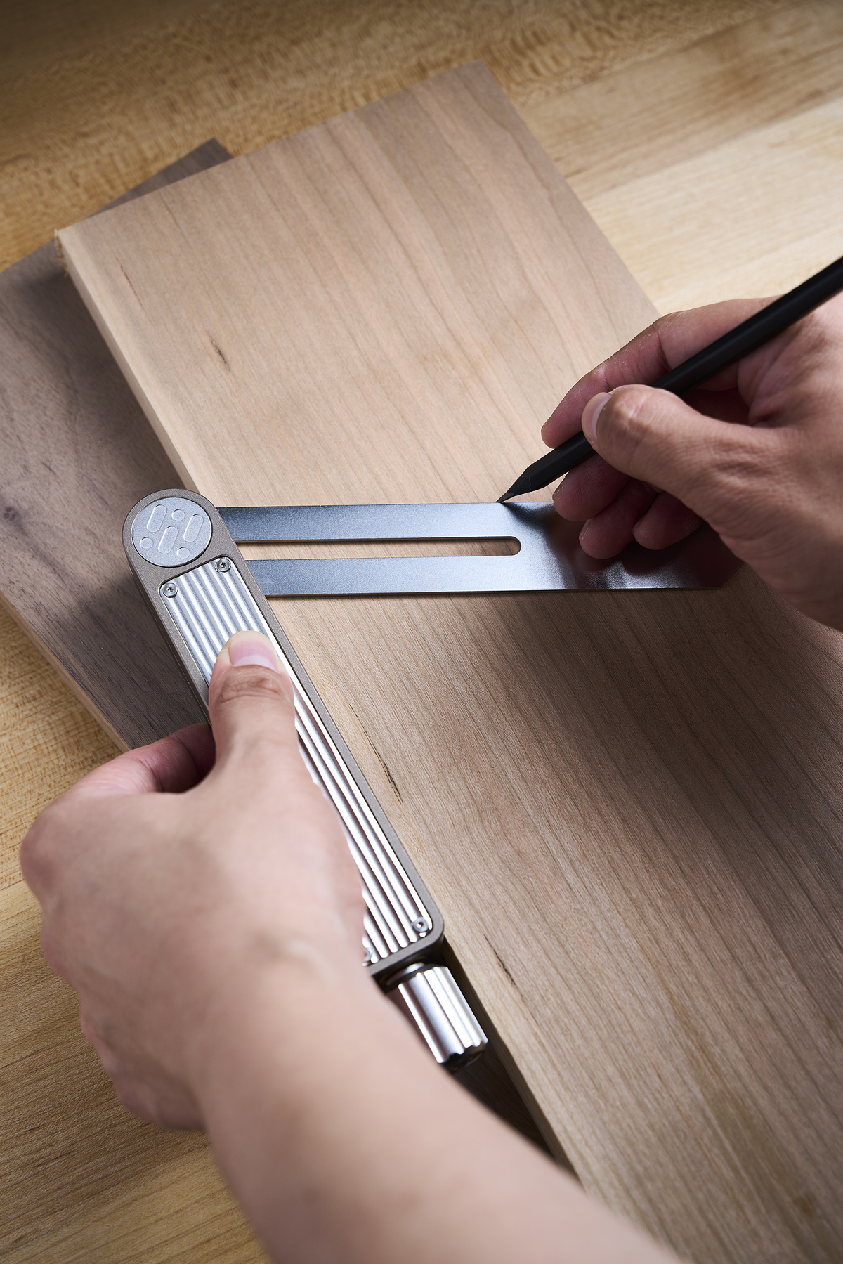 Hands using sliding bevel gauge to mark an angled line on wooden board
