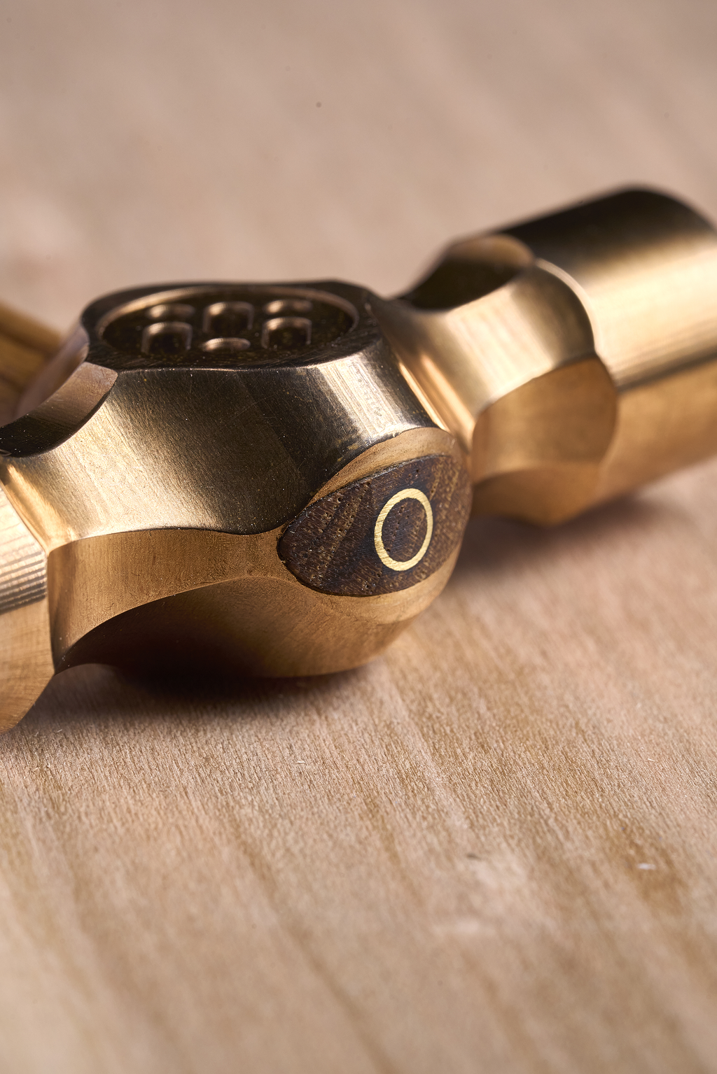 Close-up of cross peen hammer brass head and wooden handle on wood surface
