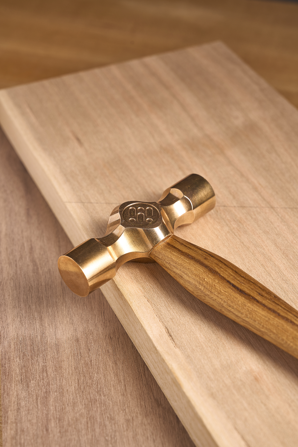 Cross peen hammer with brass cross-peen head and wooden handle on wood block